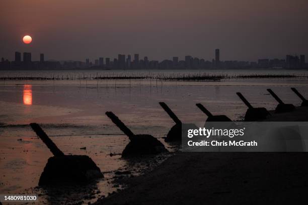 Anti-tank fortifications from previous conflicts are seen silhouetted as the sun sets over Chinese city Xiamen on April 09, 2023 in Kinmen, Taiwan....