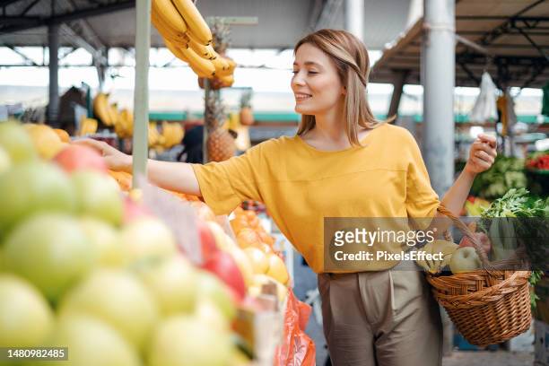 une femme achète des fruits au marché fermier - produce aisle photos et images de collection