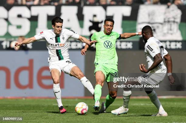 Felix Nmecha of VfL Wolfsburg battles for possession with Nico Elvedi and Marcus Thuram of Borussia Moenchengladbach during the Bundesliga match...