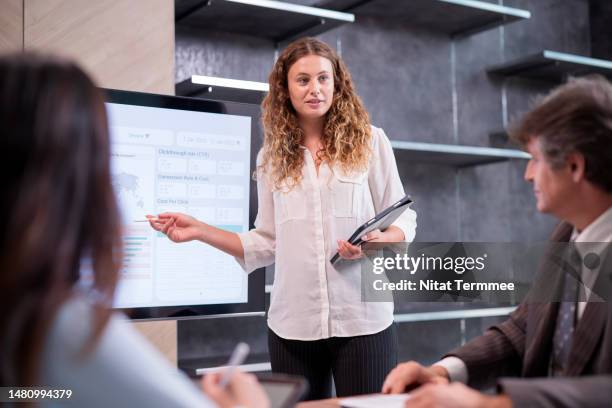 project management can reduce costs, increase revenue, and improving organizational efficiencies. project manager explaining of project timeline on a projection screen to her teams in a tech business office. - budget committee stock pictures, royalty-free photos & images