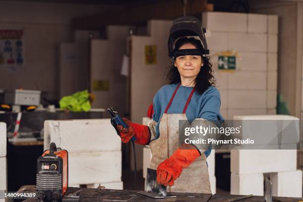 arbeiterin schweißerin mit arbeitsschutzkleidung - industriearbeiter stock-fotos und bilder