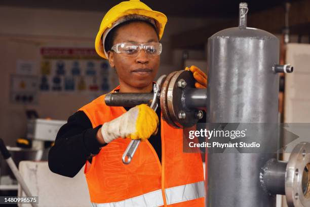 Young Woman Learning Industrial Pipe Assembly, Stockfoto