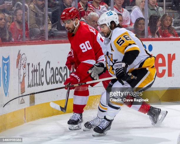 Kris Letang of the Pittsburgh Penguins battles for the puck with behind the net with Joe Veleno of the Detroit Red Wings during the third period of...