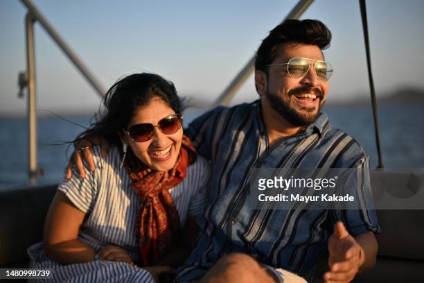a mid- adult couple sharing laughter together on a boat ride enjoying sunset. - couple india stock-fotos und bilder