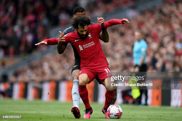 Mohamed Salah of Liverpool runs with the ball whilst under pressure from Gabriel of Arsenal during the Premier League match between Liverpool FC and...