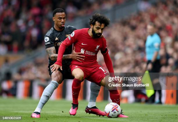 Mohamed Salah of Liverpool runs with the ball whilst under pressure from Gabriel of Arsenal during the Premier League match between Liverpool FC and...