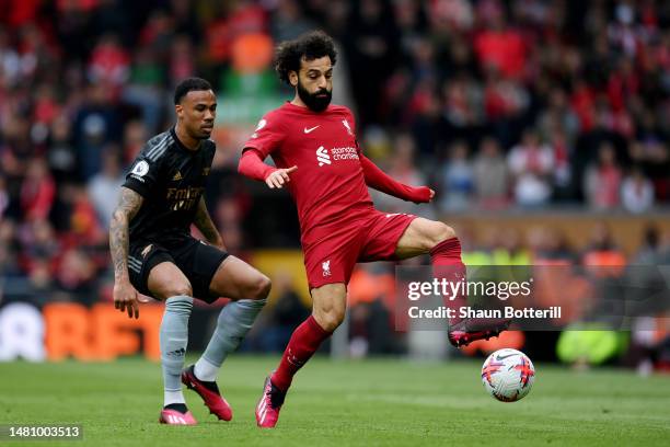 Mohamed Salah of Liverpool runs with the ball whilst under pressure from Gabriel of Arsenal during the Premier League match between Liverpool FC and...