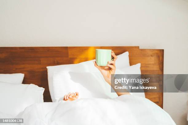 a person having morning coffee in a bed, holding a cup - hangover stock pictures, royalty-free photos & images