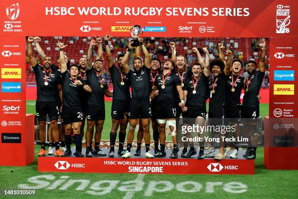The New Zealand team celebrates with the trophy after winning the cup final match against Argentina during the HSBC Singapore Rugby Sevens at the...