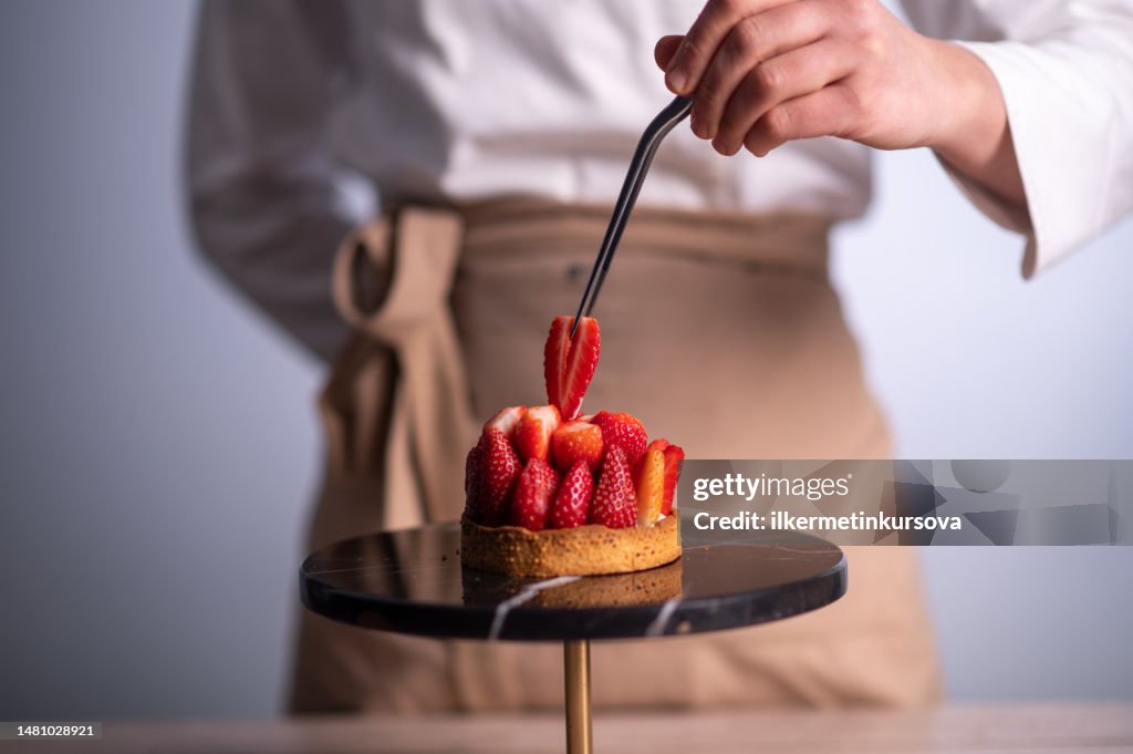 Köchin backt einen Kuchen mit Erdbeeren