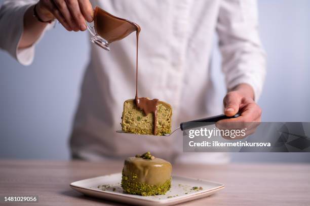 une femme chef versant de la sauce au chocolat sur un gâteau - pâtissier photos et images de collection