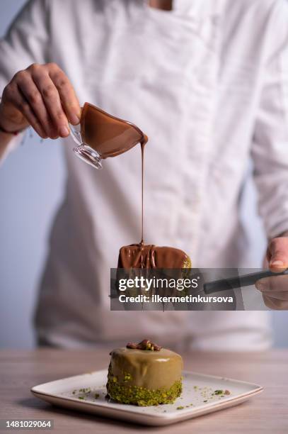 a female chef pouring chocolate sauce on a cake - finishing cake stock pictures, royalty-free photos & images