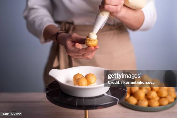 female chef making profiteroles - eclair stock pictures, royalty-free photos & images