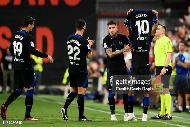 Nahuel Molina of Atletico Madrid celebrates after scoring the team's first goal with teammates, whilst holding the match shirt of Angel Correa who's...