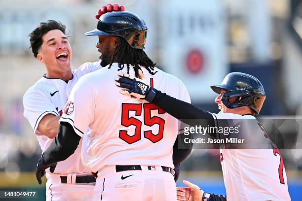 Will Brennan and Myles Straw celebrate with Josh Bell of the Cleveland Guardians after Bell hit into a fielders choice that scored Jose Ramirez for...