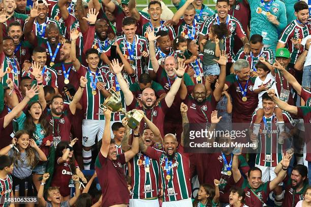 Fernando Diniz, head coach of Fluminense, Nino of Fluminense and Felipe Melo of Fluminense lift the champions trophy after winning during a...