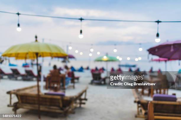 blurred and defocused background of beach sunset cafe. garlands in bokeh - goa beach party stock pictures, royalty-free photos & images