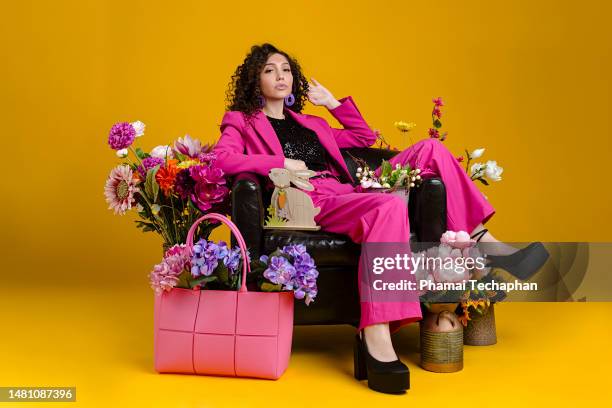beautiful woman sitting among flowers - pink suit stock pictures, royalty-free photos & images