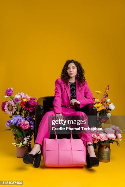 beautiful woman sitting among flowers - multi colored blazer stockfoto's en -beelden