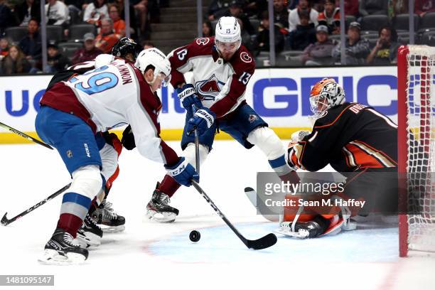 Valeri Nichushkin of the Colorado Avalanche and Nathan MacKinnon of the Colorado Avalanche poke at a loose puck as Lukas Dostal of the Anaheim Ducks...
