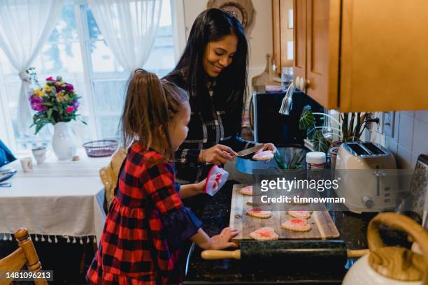 mother and daughter making heart shaped home made cookies - family small kitchen stock pictures, royalty-free photos & images