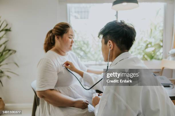 transgender male doctor doing medical exam to  obesity patient at home, medical service - obesity concept stock pictures, royalty-free photos & images