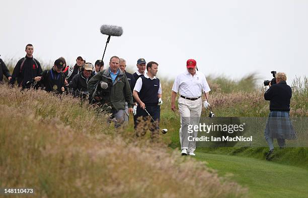 Donald Trump is accompanied by the media during the opening of The Trump International Golf Links Course on July 10, 2012 in Balmedie, Scotland. The...