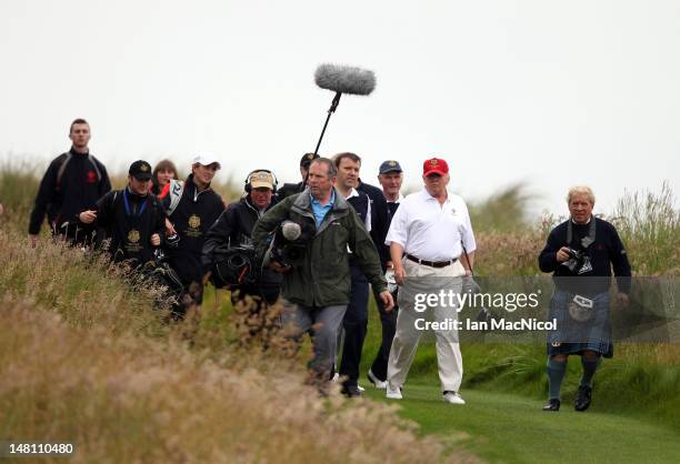 Donald Trump is accompanied by the media during the opening of The Trump International Golf Links Course on July 10, 2012 in Balmedie, Scotland. The...
