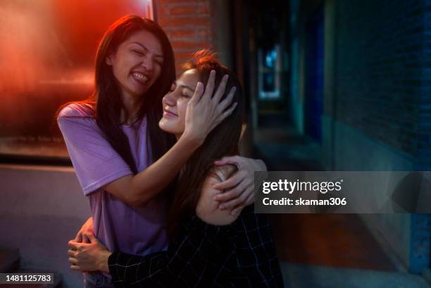 candid moment positive emotion couple asian females lesbian lgbt lovers embracing  each other at public space pride month - bi annual stock-fotos und bilder