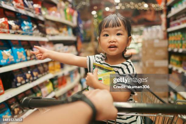 pov angle asian toddler female very happy to buying a snack and sitting in shopping cart with her parent - boy thailand stock-fotos und bilder