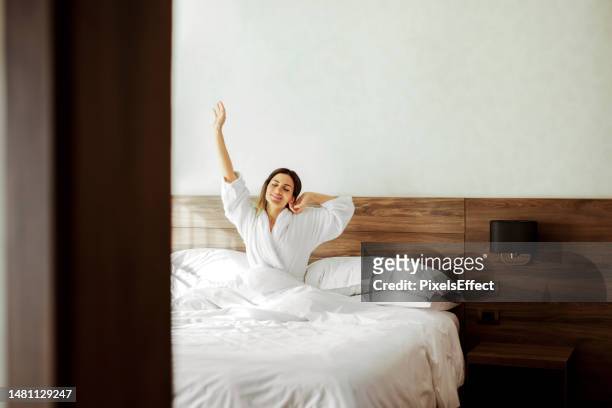 stretching her arms after sleep - comfy bed stock pictures, royalty-free photos & images