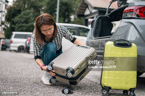 when luggage goes wrong: a woman's journey with a broken wheel - breaking and exiting stockfoto's en -beelden