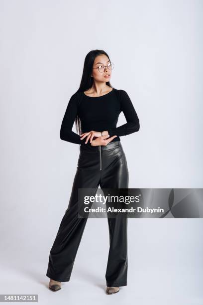 asian woman posing in a new collection of clothes on a white background studio shot - leather trousers stockfoto's en -beelden