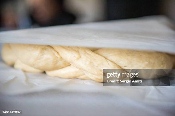 covering braided raw dough with wax paper to make italian easter bread (pane di pasqua) - braided bread stock pictures, royalty-free photos & images