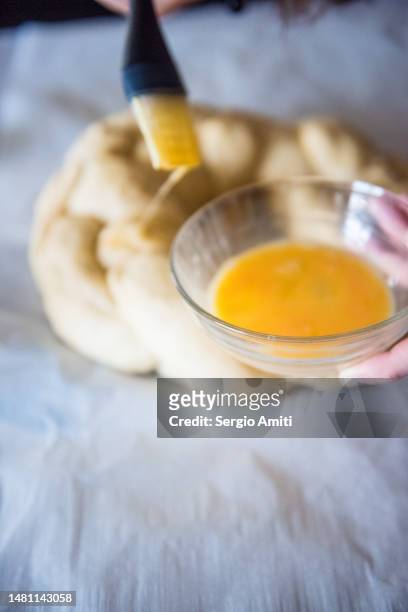brushing eggwash over braided dough to make italian easter bread (pane di pasqua) - braided bread stock pictures, royalty-free photos & images