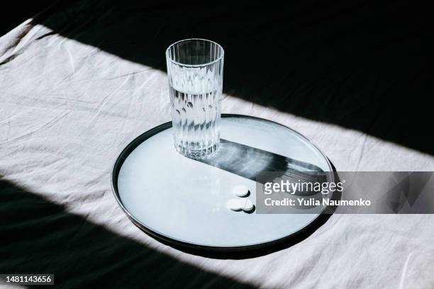 pills and a glass of water. health care and illness concept. - allergy medicine stock pictures, royalty-free photos & images
