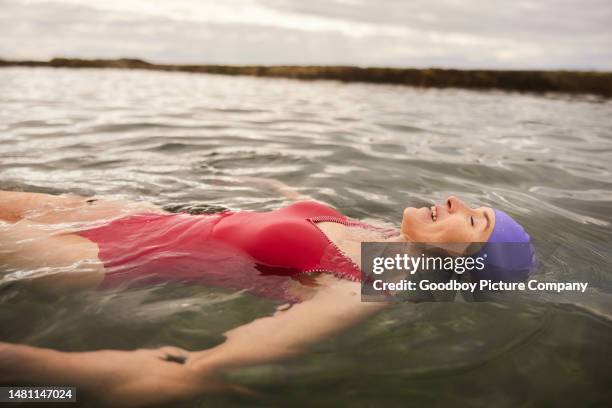 mature woman floating in the ocean with her eyes closed and smiling - swimmer stock pictures, royalty-free photos & images
