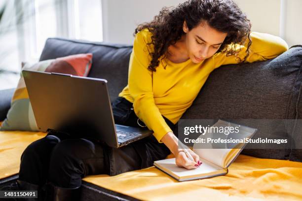 a young beautiful woman is learning at home using online help. - laatstejaars high school stockfoto's en -beelden