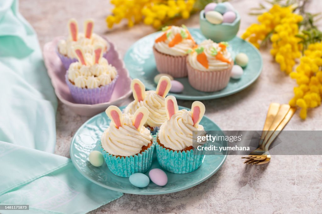 Oster-Cupcake mit Frischkäseglasur verziert mit Karotten und Hasenohren.