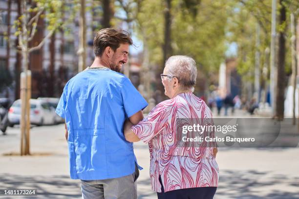 caucasian old woman walking in the city with her internal nurse. - diferença entre gerações - fotografias e filmes do acervo