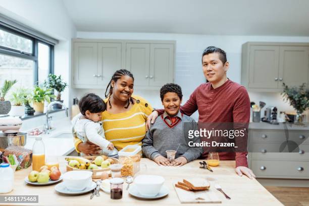 multiethnic family with two kids at home preparing breakfast and looking at camera - childhood obesity stock pictures, royalty-free photos & images