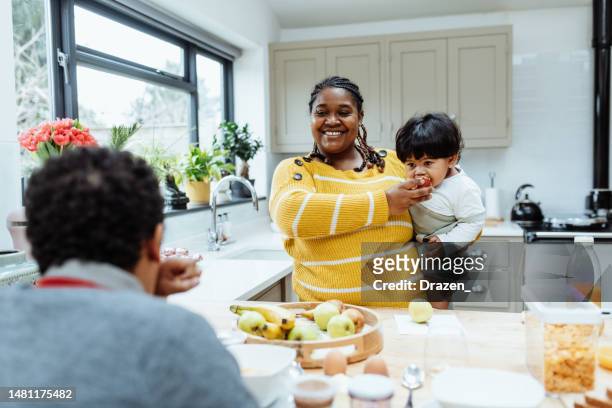asian single mother with two kids at home, preparing breakfast and feeding baby - childhood obesity stock pictures, royalty-free photos & images