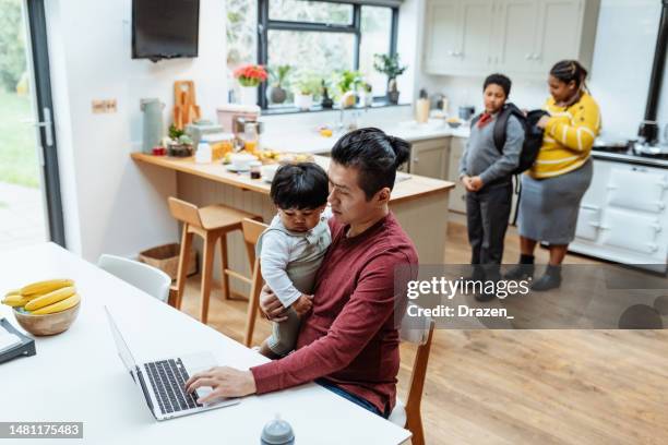 asian entrepreneur father working from home on laptop and holding baby - korean ethnicity stock pictures, royalty-free photos & images