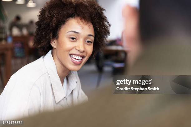 young mixed race woman smiling towards male colleague - mixed race young creatives in meeting stock-fotos und bilder