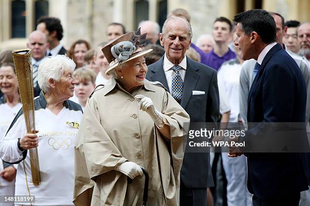 Queen Elizabeth II and Prince Philip, Duke of Edinburgh watch the Olympic torch leave Windsor Castle with the previous torch bearer Gina MacGregor...