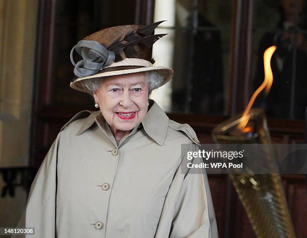 Queen Elizabeth II is shown the Olympic flame at Windsor Castle on day 53 of the London 2012 Olympic Torch Relay on July 10, 2012 in Windsor,...