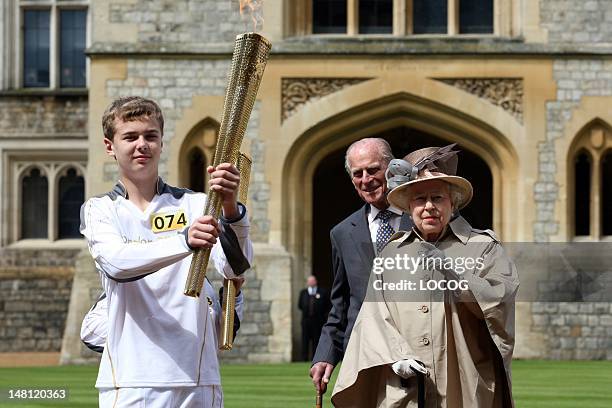 In this handout image provided by LOCOG, Queen Elizabeth II and Prince Philip, Duke of Edinburgh look on as Olympic torchbearer 074 Phillip Wells...