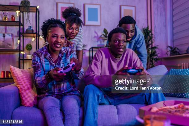 excited friends playing video games at home - adrenaline junkie stock pictures, royalty-free photos & images