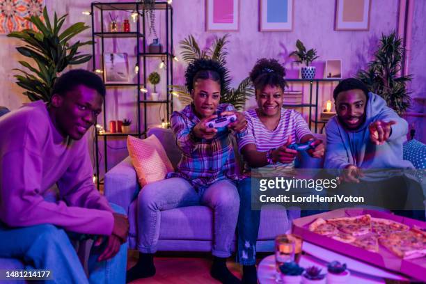 friends playing video games at the apartment - adrenaline junkie stock pictures, royalty-free photos & images