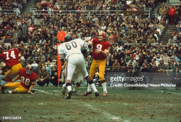 As American football player Wally Chambers , of the Chicago Bears, approaches Washington Redskins quarterback Sonny Jurgensen throws a football...